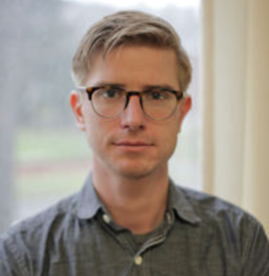 young blond man wearing glasses and green shirt 