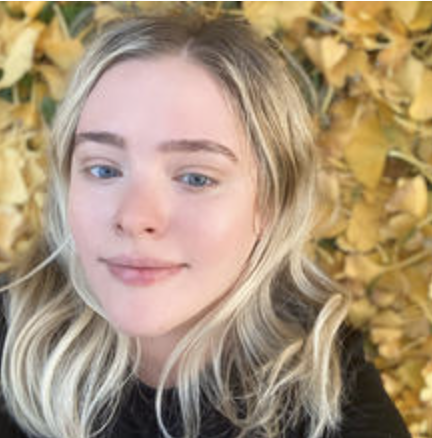 young blond woman in front of tree with gold leaves