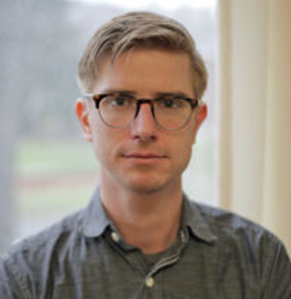 young blond man wearing glasses and green shirt