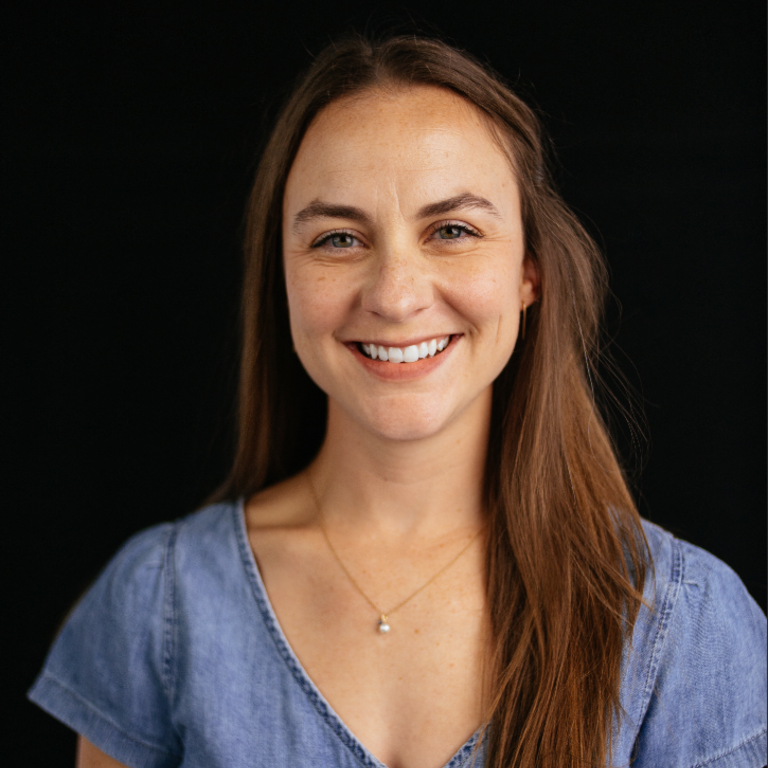 woman with long brown hair standing in front of a black background