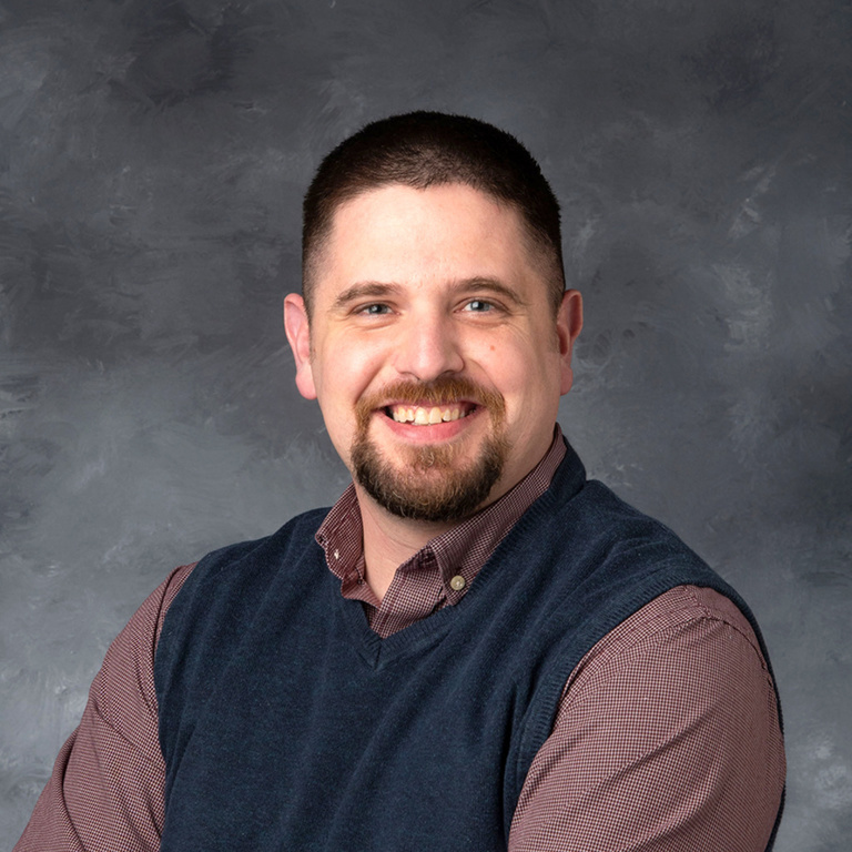 man with brown hair and a beard in a vest